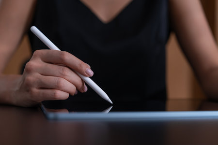 Close up of man hand with pen stylus touch or click on digital tablet, lying on desk. Concept of electronic device, website, design, creativity or work processの写真素材
