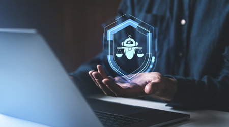 Man hand holding glowing hologram hud shield with chat bot and scales, laptop on desk. Ai regulation and compliance. Concept of artificial intelligence ethical code and securityの写真素材