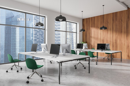 Modern coworking office with minimalist desks, green chairs, and computers. Large windows, concrete floor, and wooden wall background. Business concept. 3D Renderingの写真素材