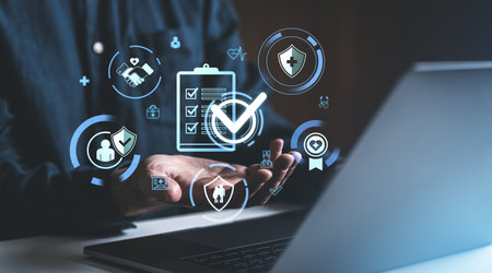 Man using laptop and hand holding glowing health insurance symbol, check mark and medical icons hologram hud. Concept of health benefit, treatment and coverageの写真素材