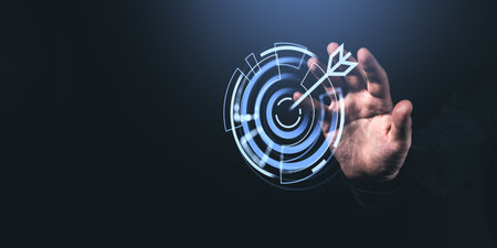 A man reaches out to touch a futuristic digital target icon with an arrow on a dark background,...