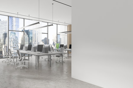 Open space office with computers on desks, large windows showing city buildings, and a blank wall in the foreground. Finance concept. 3D Rendering.の写真素材