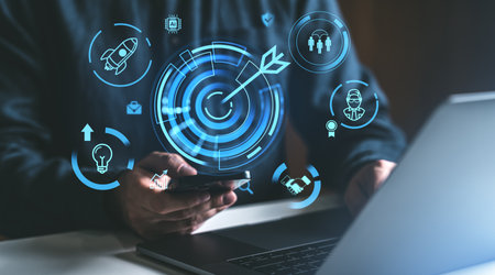 A man holding a smartphone with illuminated startup icons like rocket and target. Dark background. Concept of strategy and successの写真素材