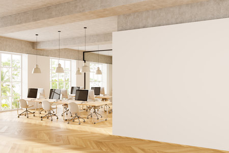 Spacious office with a blank wall, wooden floor, and computers on desks. Modern interior design concept. 3D Renderingの写真素材