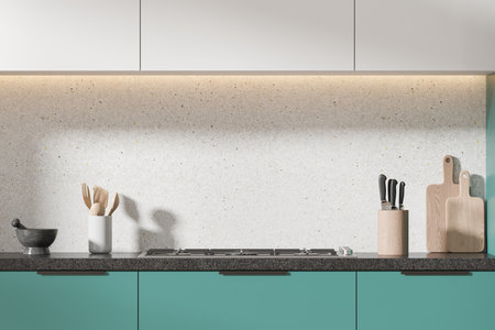 White and green home kitchen interior with gas stove and minimalist kitchenware. Cooking cabinet and dark stone counter with knives and cutting board. 3D renderingの写真素材