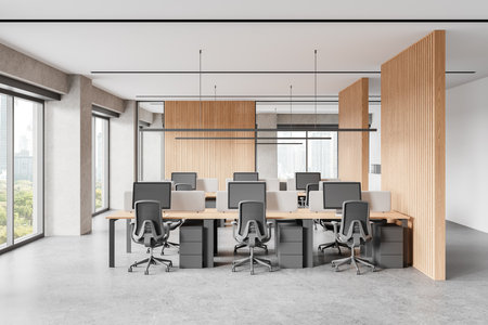 Office interior with pc computers and desks with room divider, light concrete floor. Industrial coworking zone with panoramic window on skyscrapers. 3D renderingの写真素材