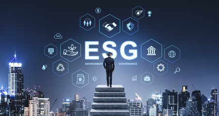 Businessman stands on steps, facing ESG icons against a cityscape backdrop. Nighttime setting, highlighting sustainability conceptsの写真素材