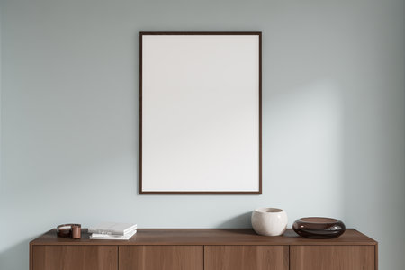 Empty framed poster on a wooden cabinet with books and decor against a light wall background. Concept of interior decor. 3D Renderingの写真素材
