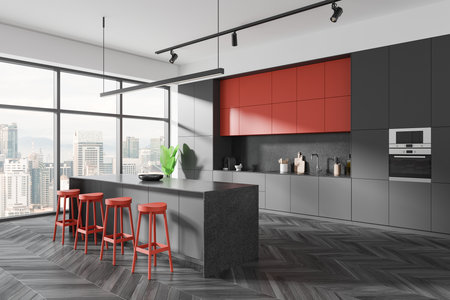 Sleek modern kitchen with red accents, large windows, and a city view. Gray cabinets, island, and stools on a herringbone floor. 3D Renderingの写真素材