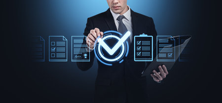 Businessman interacts with digital checklist hologram, futuristic style on dark background, representing project approval conceptの写真素材
