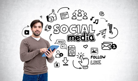 Man holding tablet with social media doodles on a white background. Concept of social media interaction and communicationの写真素材