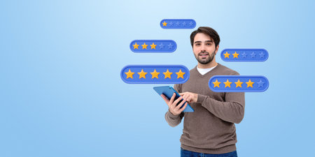 Man holding tablet with floating star rating icons, smiling on blue background. Concept of online review and customer feedbackの写真素材