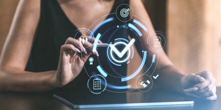 Woman interacting with digital holographic interface featuring a checkmark. Futuristic technology on a blurred background. Approval conceptの写真素材