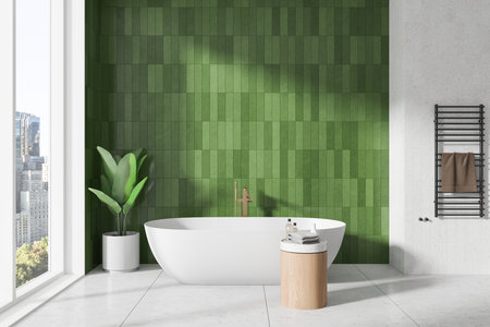 A modern bathroom featuring a white bathtub, green tile wall, and large window. Interior design with plant and towel rack. 3D Renderingの写真素材