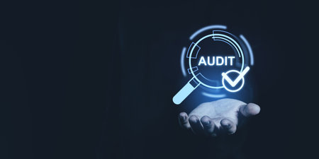 A hand holding a digital audit icon with a magnifying glass and checkmark on a dark background. Represents quality assurance and approvalの写真素材
