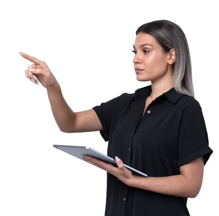 Woman holding a tablet and pointing forward while standing on a clean white background. Concept of technology, communicationの写真素材