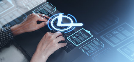 Hands typing on a laptop with holographic icons of documents and a clock on a blurred background, representing digital task managementの写真素材