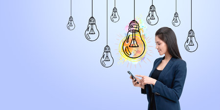 Woman using smartphone with creative lightbulb illustrations on a blue background. Represents innovation and ideasの写真素材
