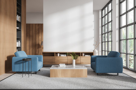 A modern living room featuring blue armchairs, wooden paneling, and a central coffee table. Bright, spacious setting with large windows and natural light. 3D Renderingの写真素材