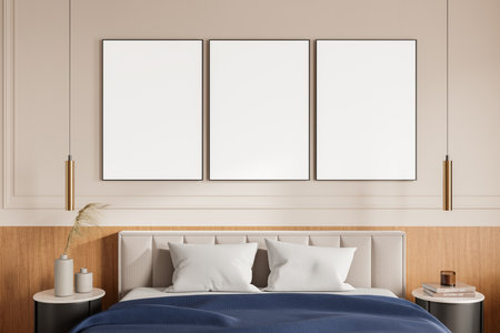 Three empty framed posters displayed on a beige wall above a bed with cushions, side tables, and pendant lights in a modern bedroom interior concept. 3D Rendering.の写真素材