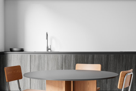 A modern kitchen interior with a round table, wooden chairs, and minimalist gray cabinets. Simple backdrop of a white wall. Concept of home luxury. 3D Renderingの写真素材