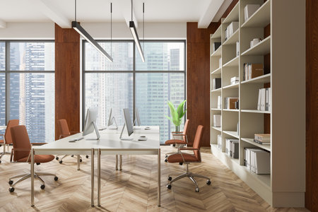 A spacious, modern office interior with desks, computers, bookshelves, and large windows overlooking skyscrapers. Wooden walls and parquet flooring. Business concept. 3D Rendering.の写真素材