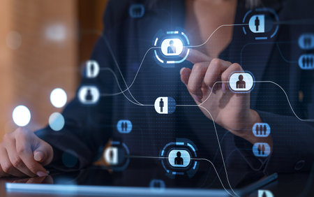 A businesswoman interacting with a digital interface displaying network icons. Futuristic design with blue tones. Concept of technologyの写真素材