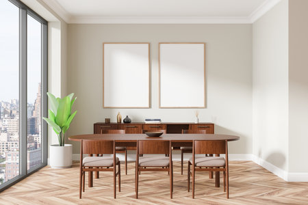 Bright dining room featuring two blank framed posters on a beige wall, wooden table and chairs, large window, chevron floor. 3D Renderingの写真素材