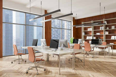 A modern office interior with desks, computers, and chairs in an open space layout. Large windows showcase a cityscape background. Concept of coworking space. 3D Renderingの写真素材