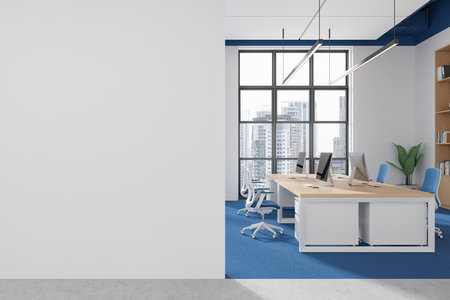 Empty white wall on left side of image, modern office setup on right with desks, computers, large windows. Concept of open space office. 3D Rendering.の写真素材
