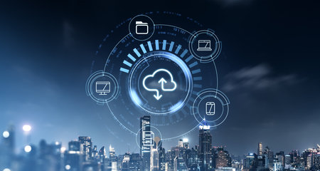 Cloud storage icons displayed in the center, with digital devices surrounding, over a blurred city skyline at night. Concept of global digital storage serviceの写真素材