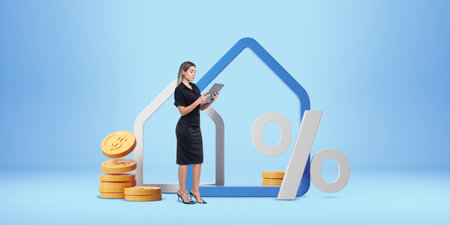 Professional woman using a tablet near house outline, gold coins, and percentage sign on blue background. Concept of real estate and mortgageの写真素材