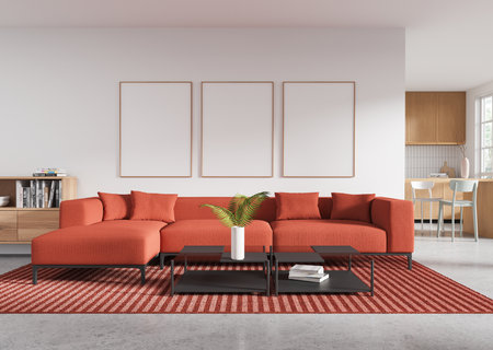 Modern living room with blank poster frames above a red sectional sofa, striped rug, andcoffee tables. Wooden furniture and kitchen in background. 3D Rendering.の写真素材