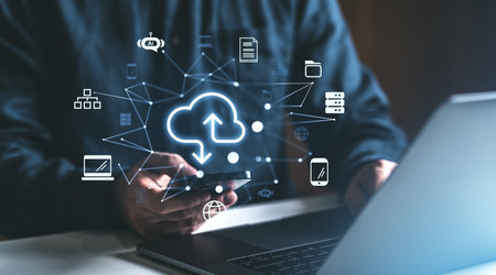 Man interacting with cloud storage icons on a laptop and smartphone. Digital and network-based connection on a dark background, concept of online data managementの写真素材
