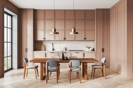 Modern kitchen featuring warm pink cabinetry, wooden dining table with blue upholstered chairs. Bright ambiance with natural light. 3D Renderingの写真素材