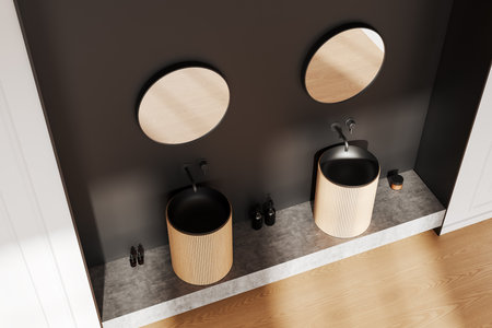 A sleek bathroom interior featuring two round mirrors, modern sinks with wooden accents, and a dark wall, all set on a wooden and stone-textured background. Concept of contemporary home decor. 3D Rendering.の写真素材