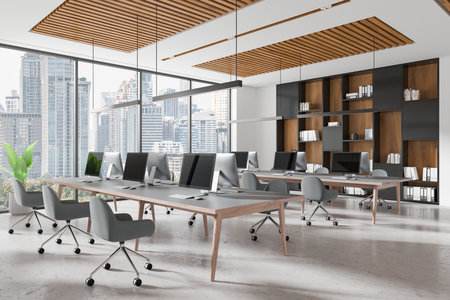 Contemporary open-space office interior with desks, computer setups, and cozy chairs, featuring loft-style decor, large windows, and cityscape views. Business concept. 3D Rendering.の写真素材