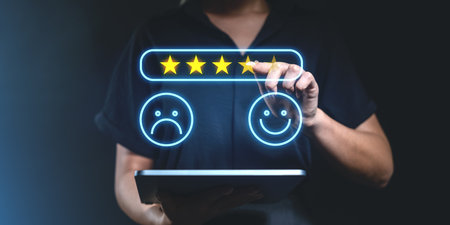 A person using a tablet to give a five-star rating with glowing satisfaction icons on a dark background. Concept of feedback and customer experienceの写真素材