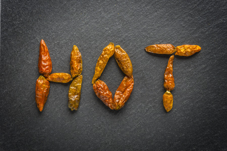 Red hot chilli peper on black background written hotの写真素材