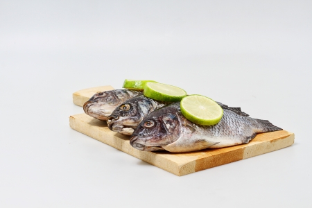 fresh fishes on cutting board, white backgroundの写真素材