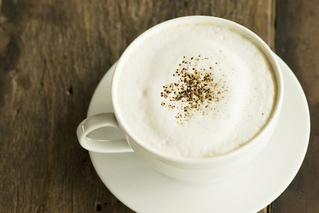 cappuccino coffee in white cup on wooden backgroundの写真素材