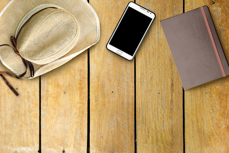 Overhead smartphone hat and notebook on old wooden deskの写真素材