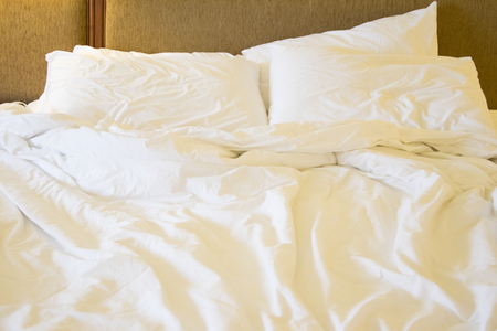 Messy white bed and pillow, in the morningの写真素材