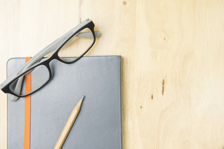 Glasses and brown pencil with notebook on work space wooden. top view, flat lay concept.の写真素材