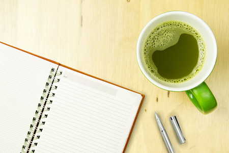 Open notebook and pen with greentea on wooden background. top view, flat lay concept.の写真素材