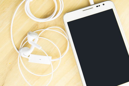 mobile phone and headphones on wood background with space.の写真素材