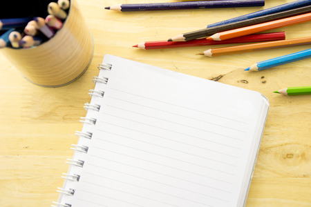 Top view notebook paper. Colorful colored Pencils on wooden table.の写真素材