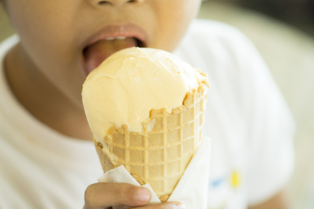 young boy Eating vanilla ice cream in waffle cone.の写真素材