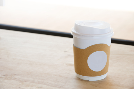Hot coffee in paper cup isolated on wood table background. with copy space.の写真素材
