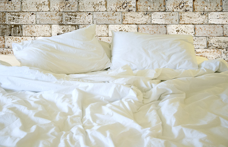 Messy white bed and pillow, in the morningの写真素材